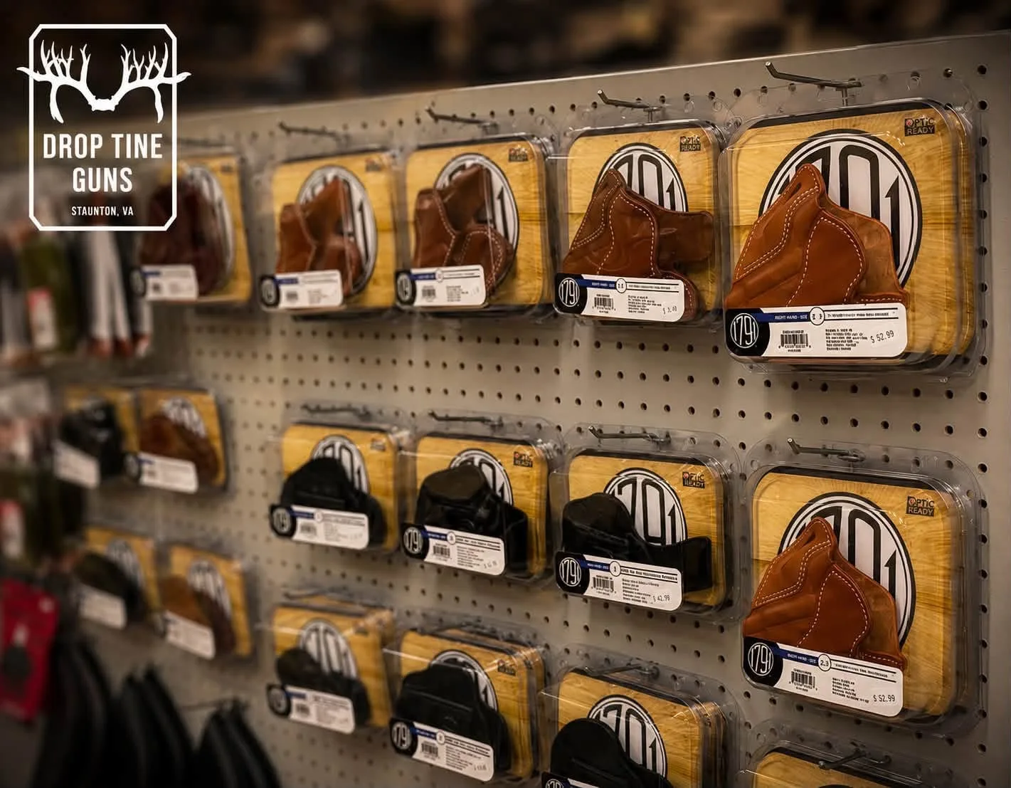 Holsters and accessories on the pegboard wall at Drop Tine Guns