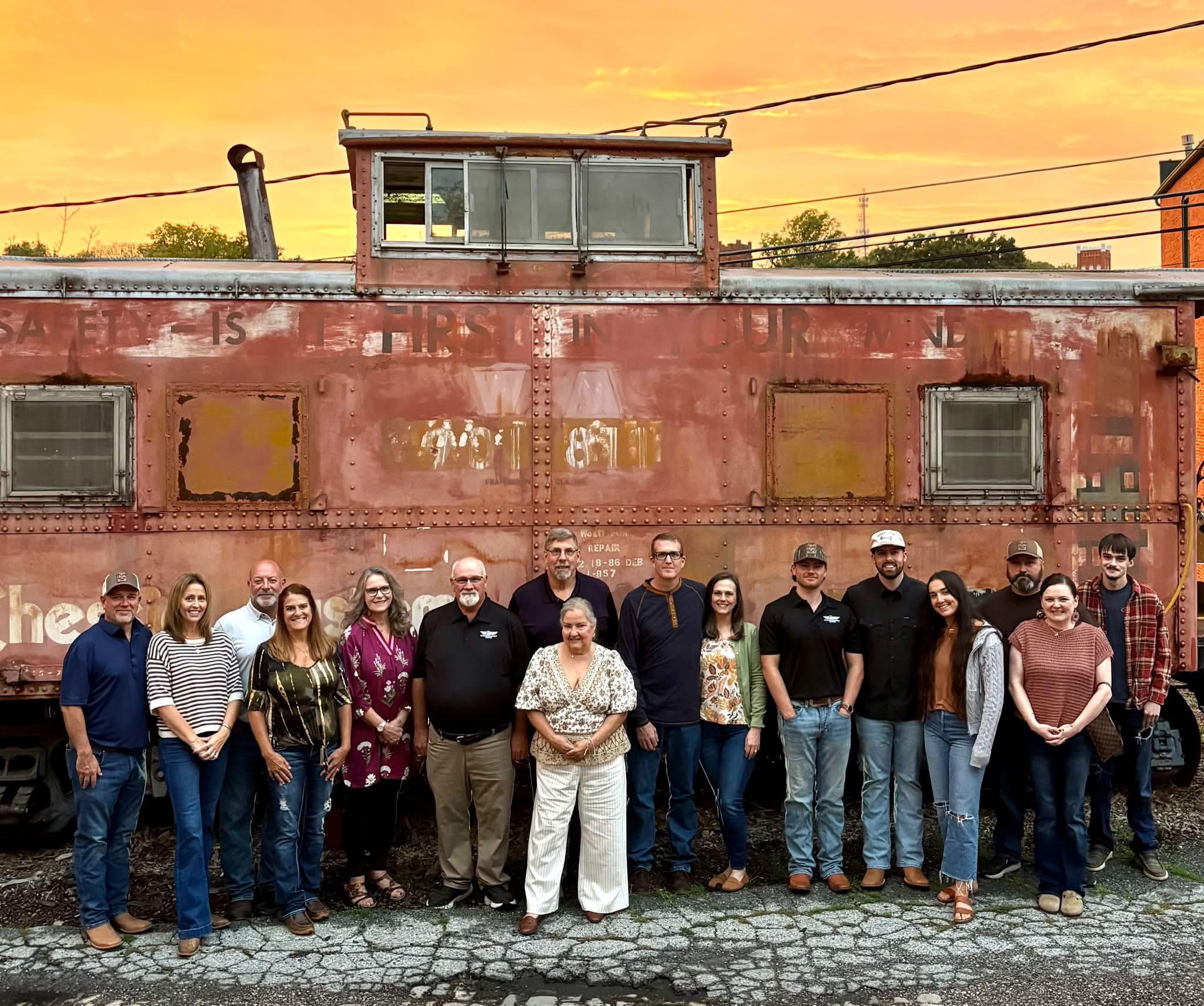 The Drop Tine Guns family in front of a red caboose at sunset